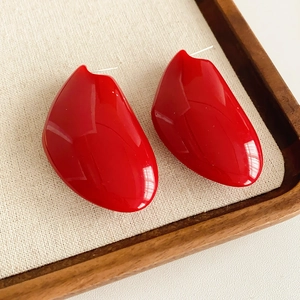 Détail des boucles d'oreilles en résine rouge en forme de cœur sur un tissu beige