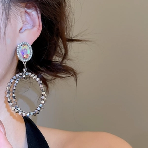 Détails de boucles d'oreilles argentées avec cristaux irisés et doubles anneaux en métal