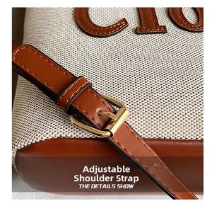 Adjustable brown leather strap detail with gold buckle on a canvas tote shoulder bag