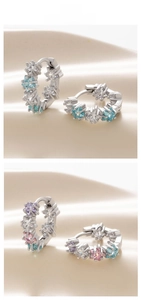 Detail view of colorful star-shaped zircon hoop earrings on a luxury cream background