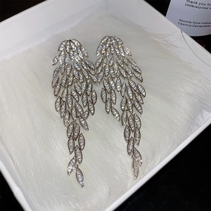 Detailed view of silver feather earrings with pavé crystals in a white gift box