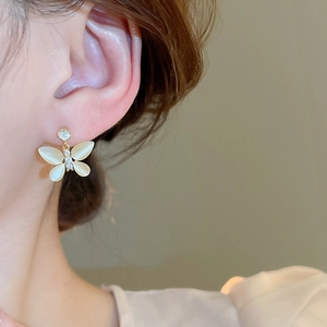 Detail shot of a butterfly earring with opal wings and cubic zirconia on model's ear