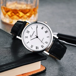 Macro detail of Ganwa quartz watch with silver bezel and black leather strap on notebook