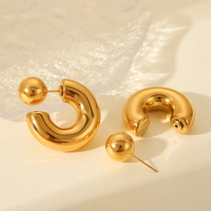 Golden stainless steel C-shaped hoop earrings with ball stud design on a glass surface
