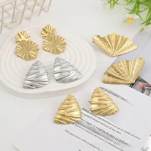 Macro detail of molten lava style irregular geometric stud earrings in gold and silver