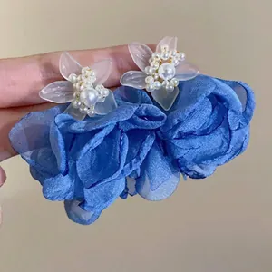 Detail of oversized resin flower earrings with pearl stamens and navy blue fabric petals