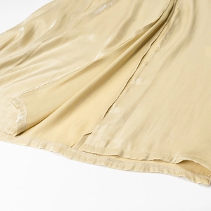 Nahaufnahme von goldenem Satinstoff mit glänzendem Finish und eleganten weichen Falten