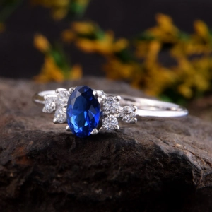 Elegante zilveren ring met een ovale saffierblauwe edelsteen en fonkelende zij-diamanten