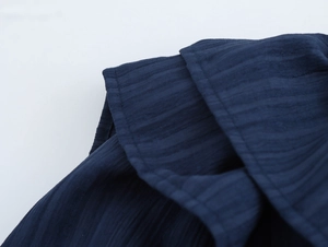 Detailed macro view of dark blue textured fabric with ruffles and pleated sewing details