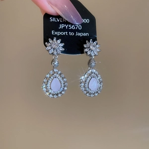 Vue détaillée des boucles d'oreilles fleur en argent avec zircon et gouttelette mauve