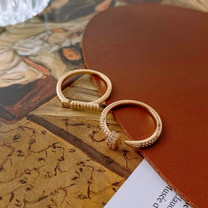 Macro view of gold-plated nail ring and pavé band on vintage paper and leather heart