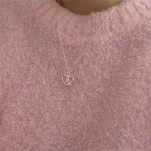 Detail of silver heart woven pendant on fine link chain over soft pink background