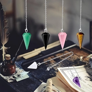 Retro still life of hexagonal crystal pendulums with silver chains on vintage book pages