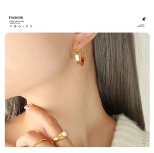 Detailed view of large gold hoop earrings and pearl ring set on model skin