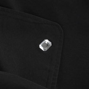 Gros plan détaillé d'une boucle en cristal rectangulaire sur une robe blazer noire