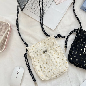 Floral drawstring crossbody bags in cream and black with striped woven shoulder straps