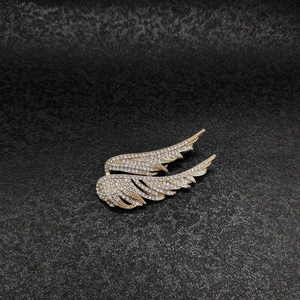 Detailed view of luxury gold wing brooch encrusted with sparkling white rhinestones