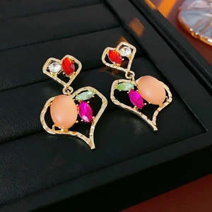 Dettaglio ravvicinato di orecchini vintage a cuore in oro con pietre preziose colorate