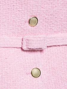 Détail du tissu en tweed rose avec boutons en métal doré texturé et couture fine