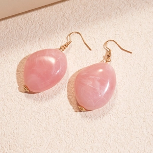 Macro shot of pink marble pattern resin oval earrings with elegant gold hooks