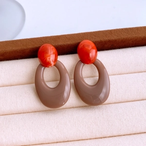 Detailed macro view of oval acrylic earrings with red marble beads on velvet display
