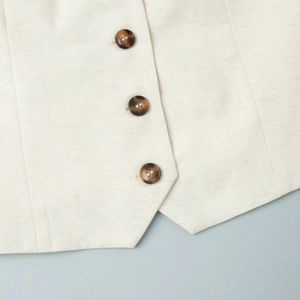 Close-up of beige linen vest fabric texture with brown tortoiseshell buttons detail
