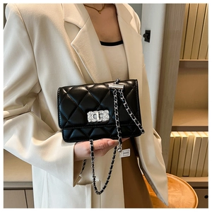 Close-up of black quilted crossbody bag featuring silver chain strap and metal clasp