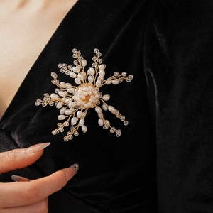 Detailed view of handmade pearl flower brooch pinned on black velvet dress for elegance