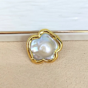 Macro detail of baroque pearl set in an artistic fluid golden metal floral frame