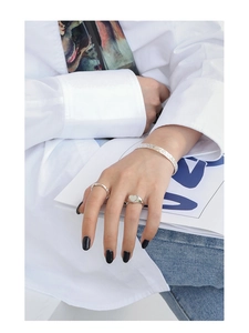 Detail of silver S925 heart shell ring and textured open bangle on female model