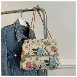 Close-up of floral tapestry chain bag with intricate embroidery on a denim jacket