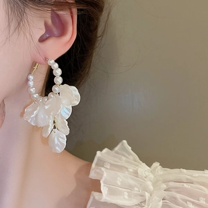 Detailed close-up of a pearl beaded hoop earring with elegant white petal tassels