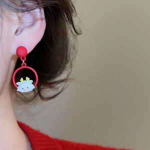 Detail of red festive lion dance drop earrings worn by a model against a warm background
