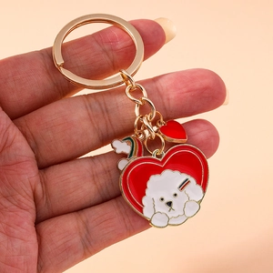 Handheld view of cartoon Bichon dog keychain with rainbow heart and gold finish