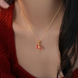 Gold plated horse pendant necklace with red enamel and zircon on a red sweater background