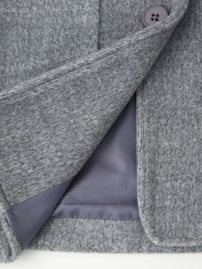 Detailed close-up of grey wool fabric texture with purple lining and a matching button