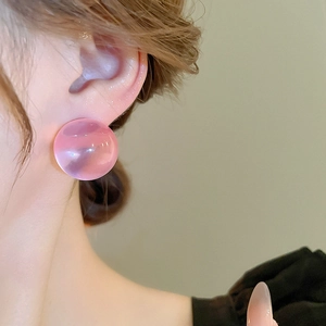Détail d'une boucle d'oreille bulle en résine rose translucide sur mannequin élégant