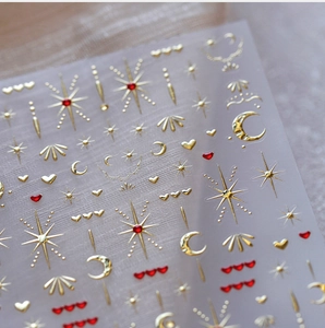 Macro shot of gold and red star moon heart embossed nail art stickers with metallic texture