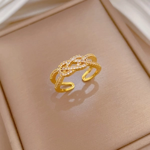 Macro shot of gold-plated twisted cross ring featuring micro-pave white zircon details