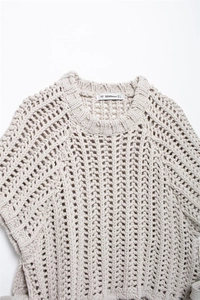 Detail of chunky knit texture and neckline on beige sweater with brand label