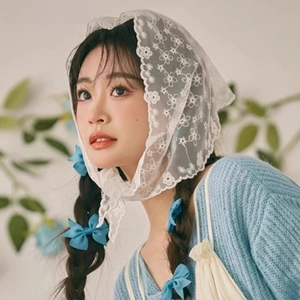 Close-up of white lace triangle kerchief with daisy embroidery and blue satin bow clip