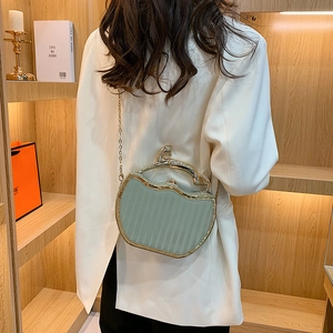 Light green apple-shaped handbag featuring a gold cat handle and chain strap