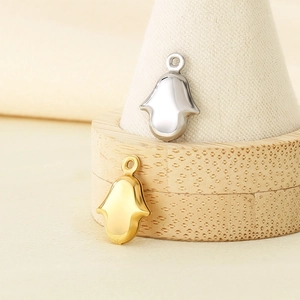 Detailed view of silver and gold Hamsa hand charms on a wooden display stand
