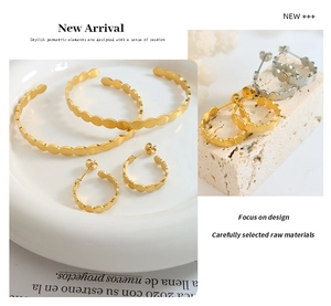 Detailed view of scalloped edge gold earrings and matching bracelet on a stone stand