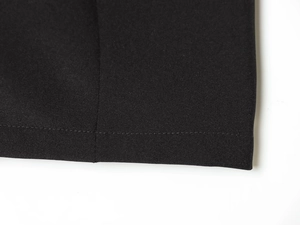 Detailed close-up of tight woven fabric and flat machine stitching on dress hem