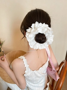 Detail of white double-layered lace hair scrunchie with intricate floral embroidery