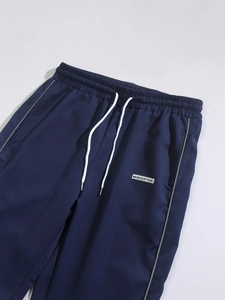 Detailed close-up of dark blue woven jogger waist with white drawstring and logo