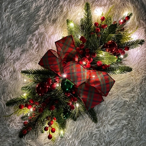 Detail of Christmas teardrop swag with red berries and warm LED lights on plush background