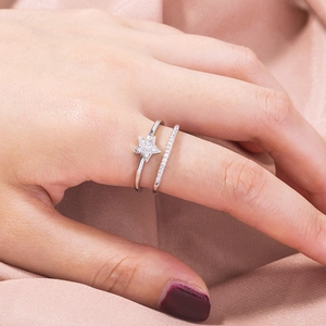 Macro shot of double-layered silver star ring with zircon inlay on silky pink fabric