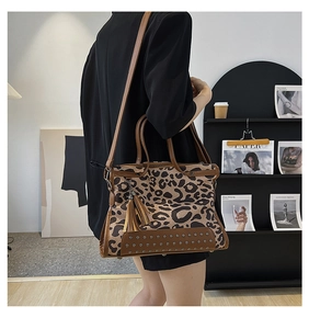 Detail of leopard print handbag with metal studs and decorative fringe tassel charm